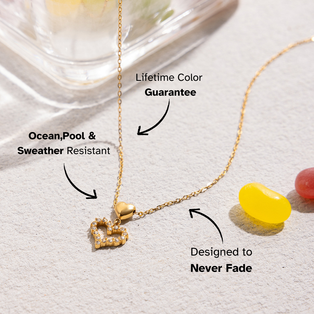 Gold necklace with heart pendant on a textured surface with text highlighting features.