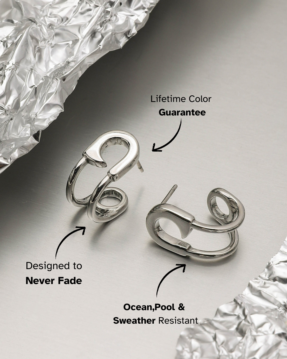 Silver hoop earrings on a reflective surface with text about color guarantee and weather resistance.
