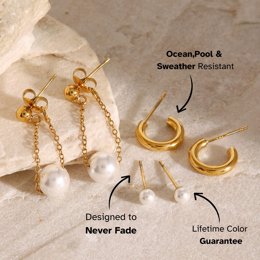 Three-pair gold earring set with pearl studs, hoops, and dangling pearls on beige stone backdrop