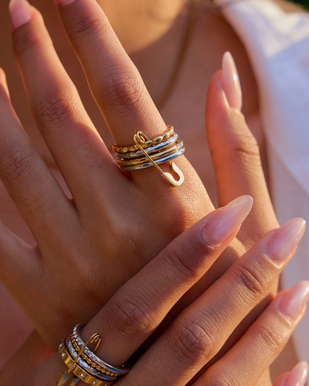 Close-up of a hand wearing multiple gold rings with a blurred background