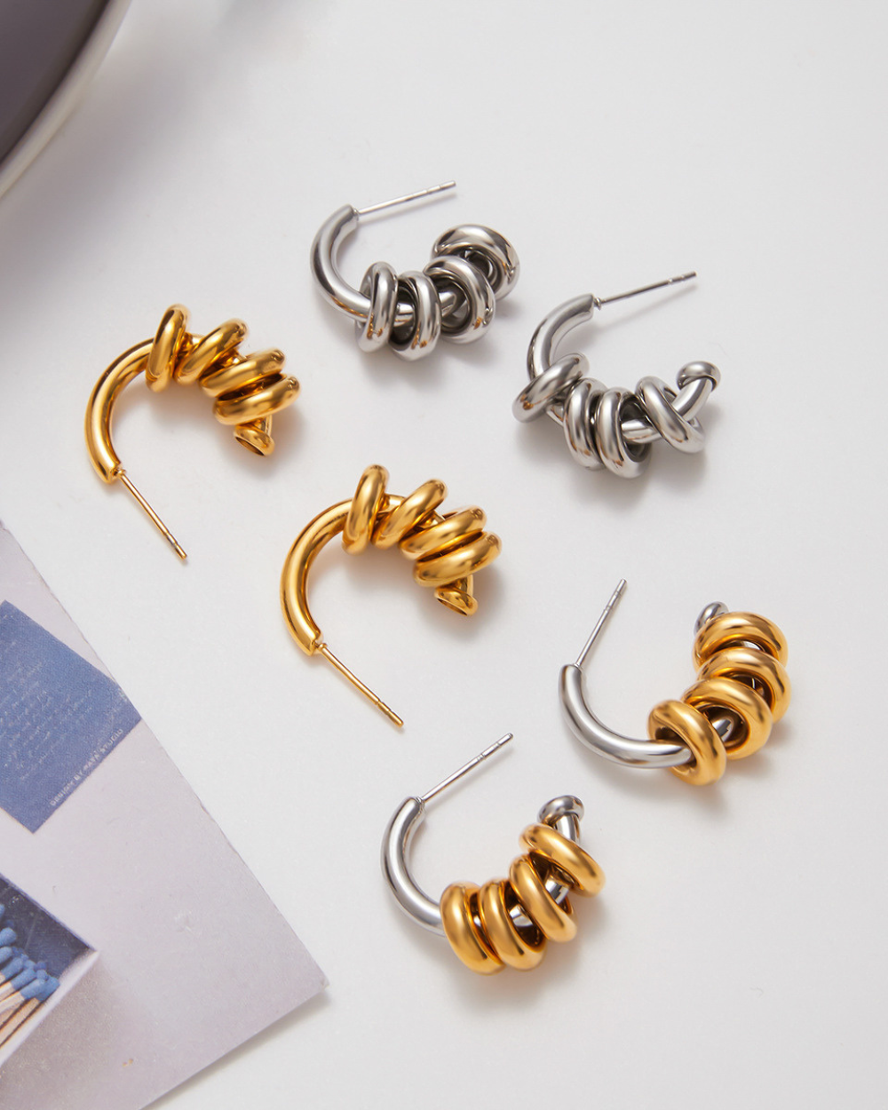 Set of gold and silver spiral hoop earrings on a white surface.