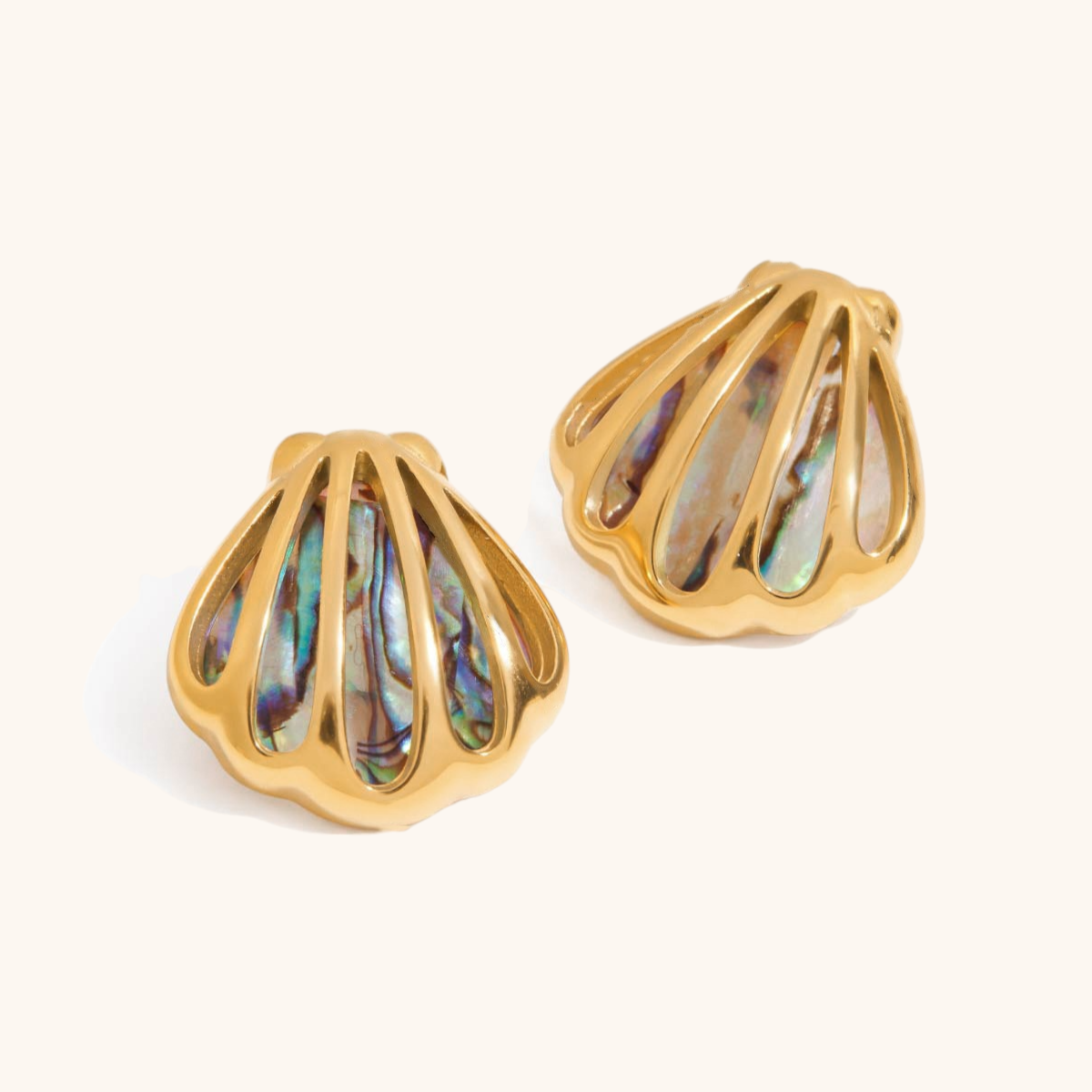 Pair of golden starfish earrings with abalone shell inlays on white background