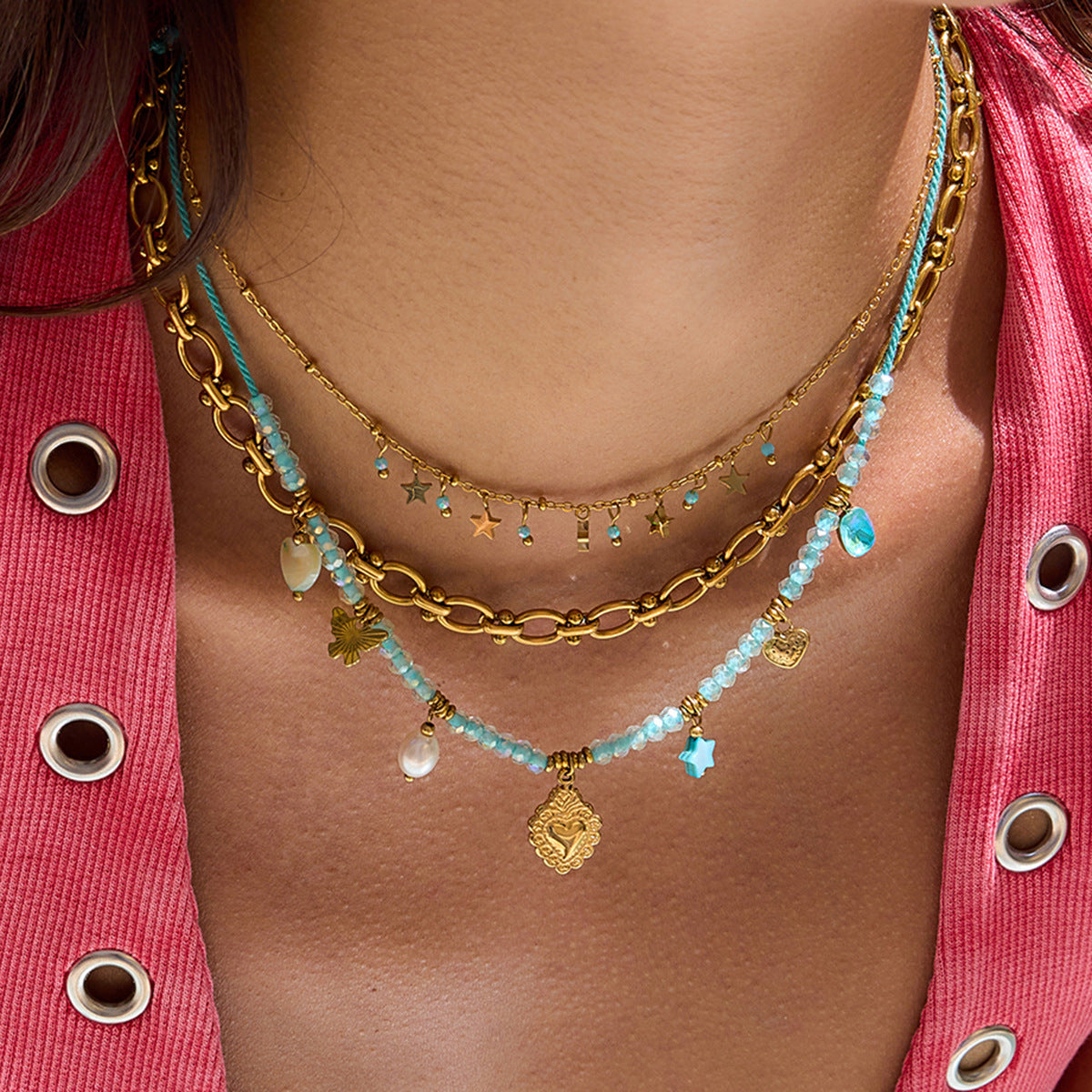 layered necklace set on model with pink tank top featuring blue beaded charm necklace