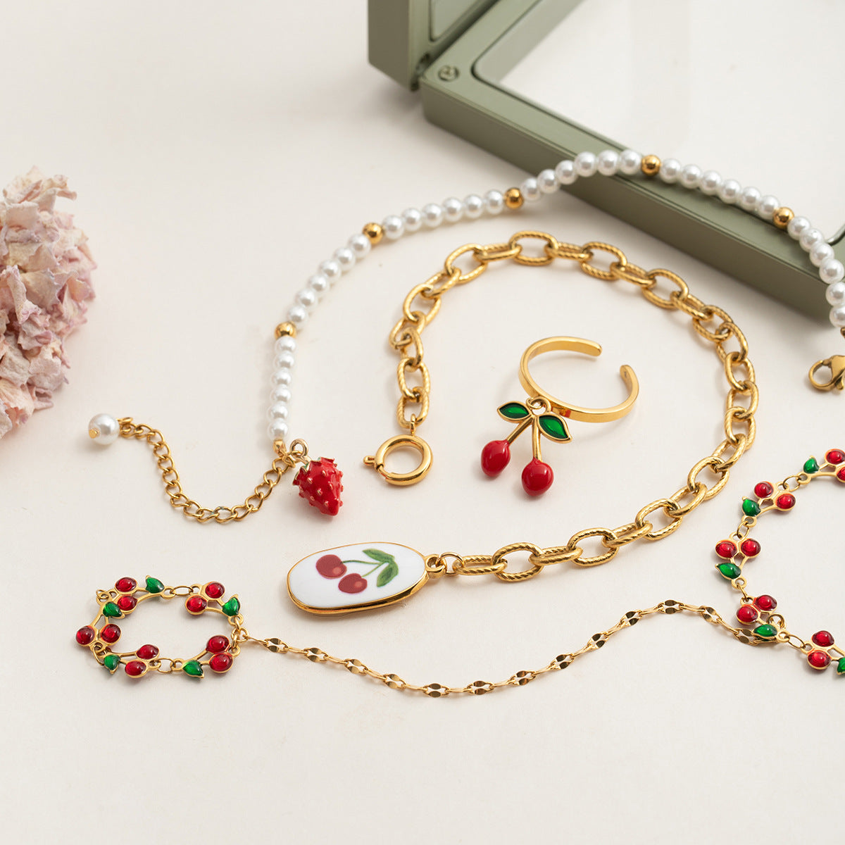 Isolated image of cherry bracelet and ring set with green leaves and red enamel berries