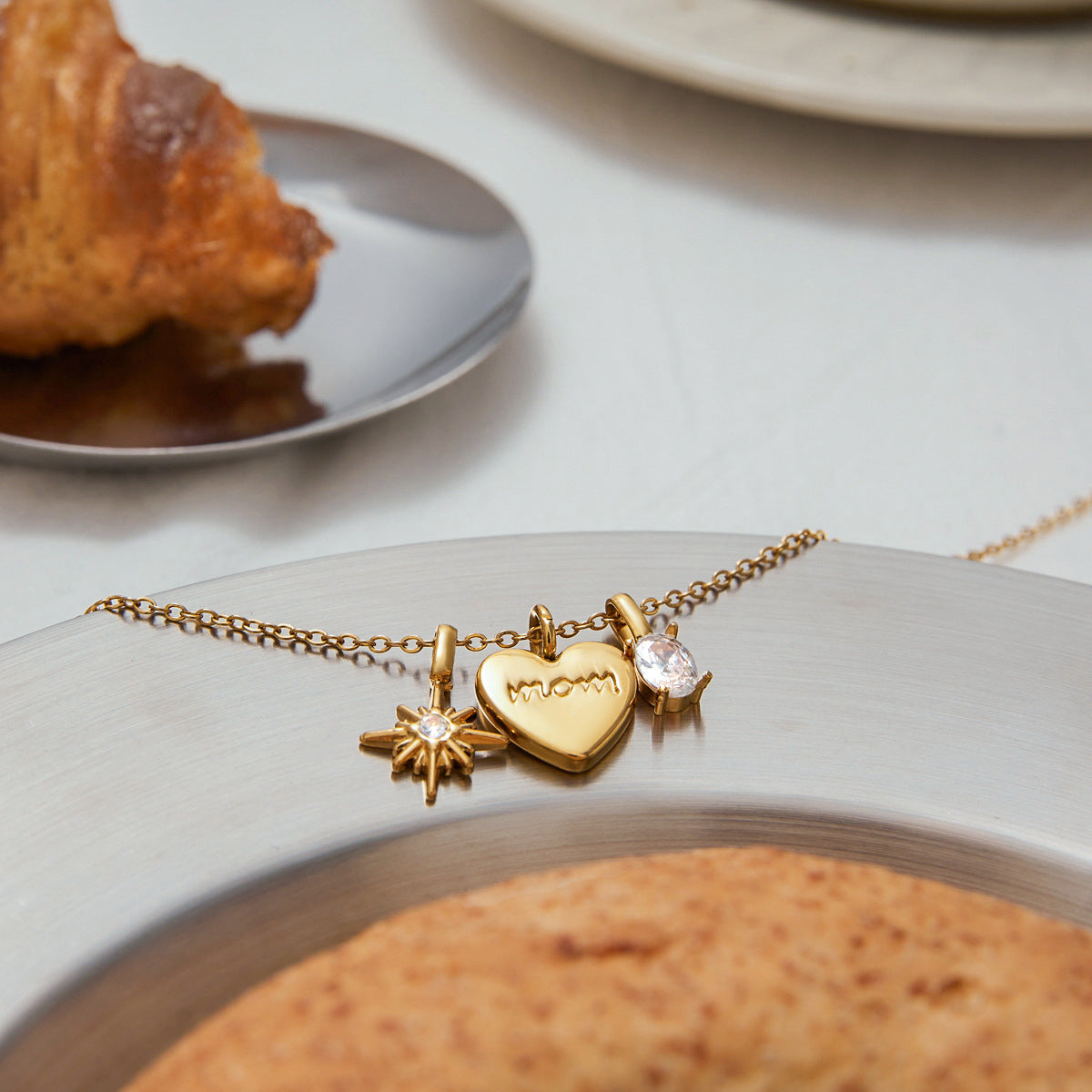 Flat lay of adjustable gold chain necklace with three gold pendants