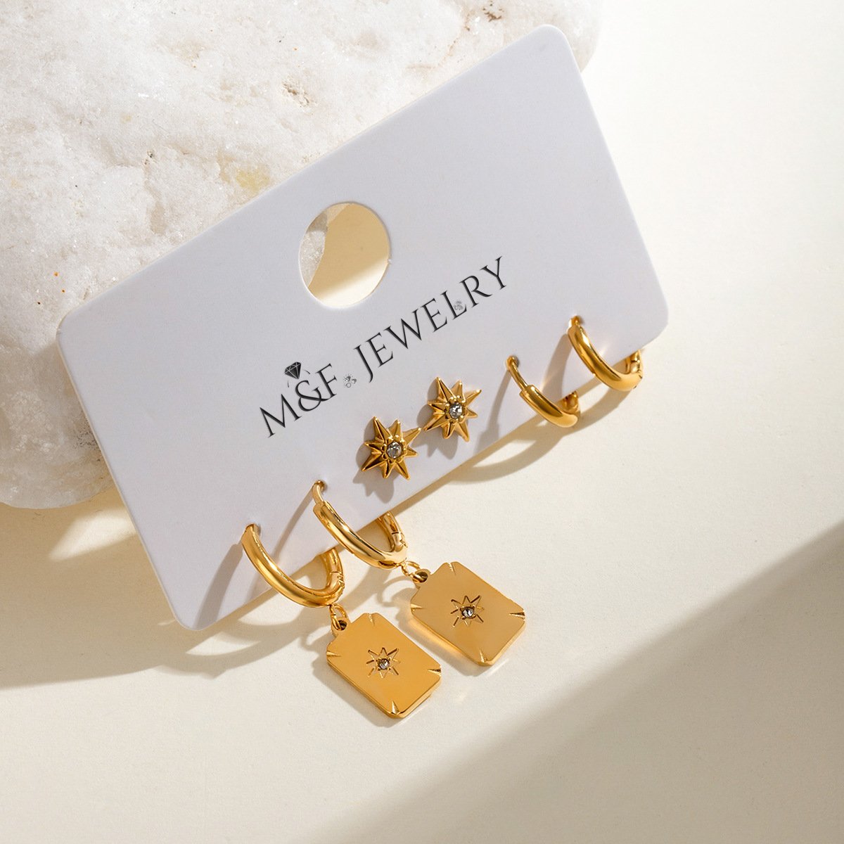 M&F Jewelry card displaying three-pair celestial gold earrings in natural light