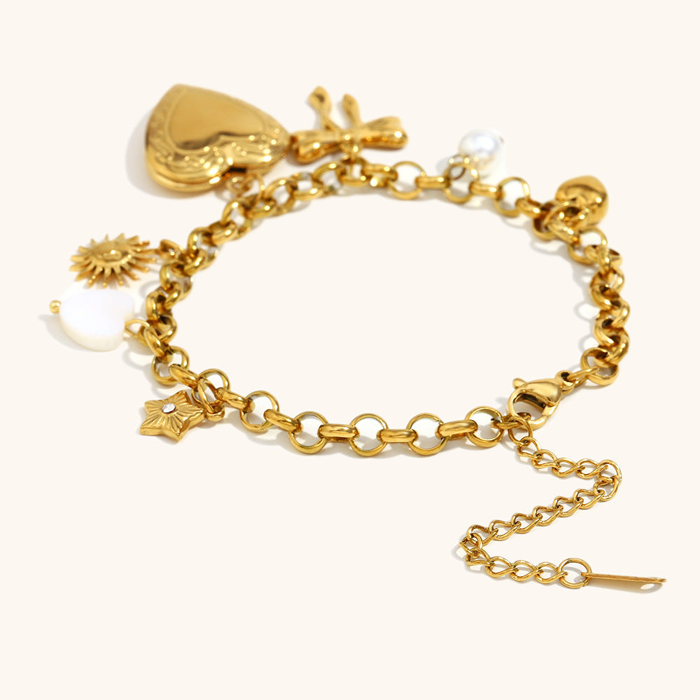 Heart locket bracelet with sun, pearl and bow charms, displayed on white backdrop