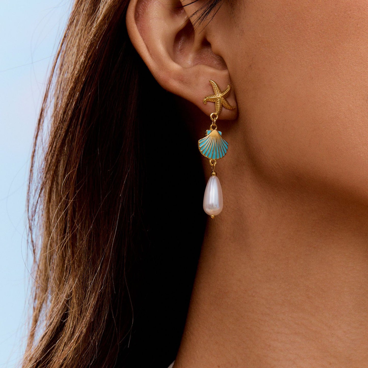 Earrings styled on beach scene with soft lighting and a splash of summer mood