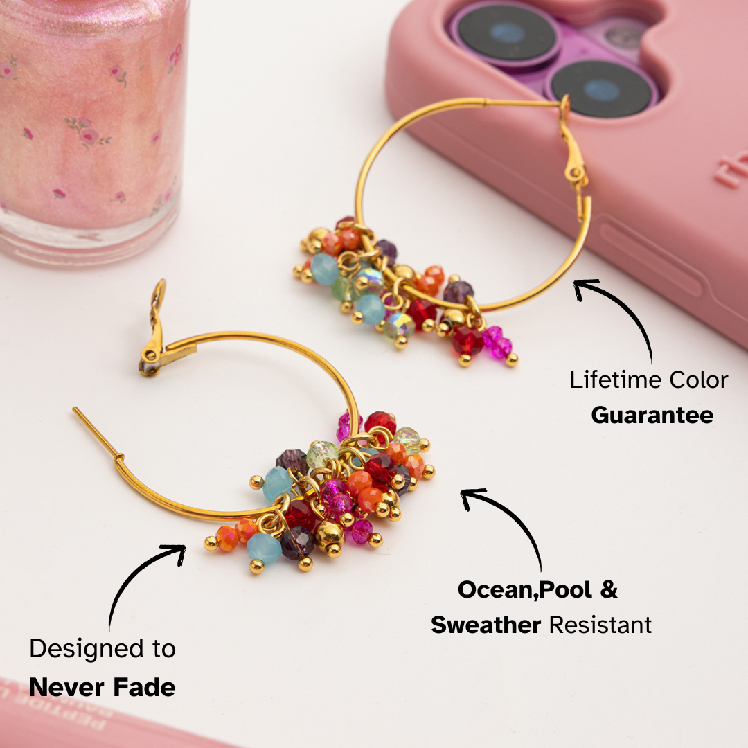 Colorful hoop earrings with gold accents on a white surface, next to a pink phone case.