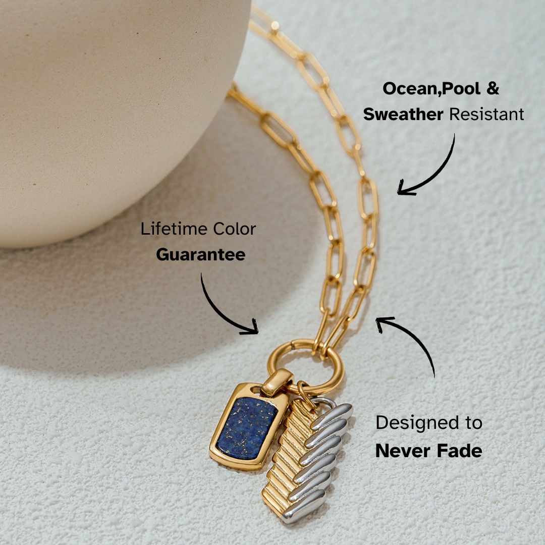 Flat-lay shot of dual-tone pendant necklace with rectangular lapis charm and metallic feather