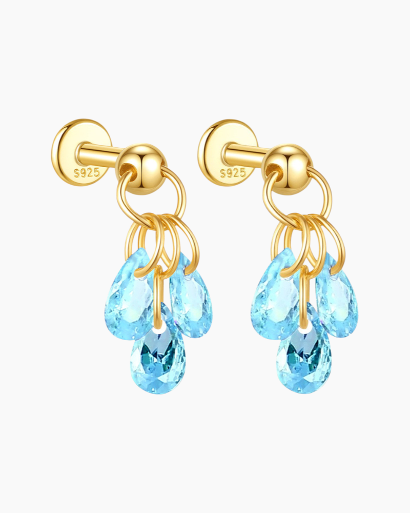 Gold earrings with blue teardrop-shaped crystals on a white background
