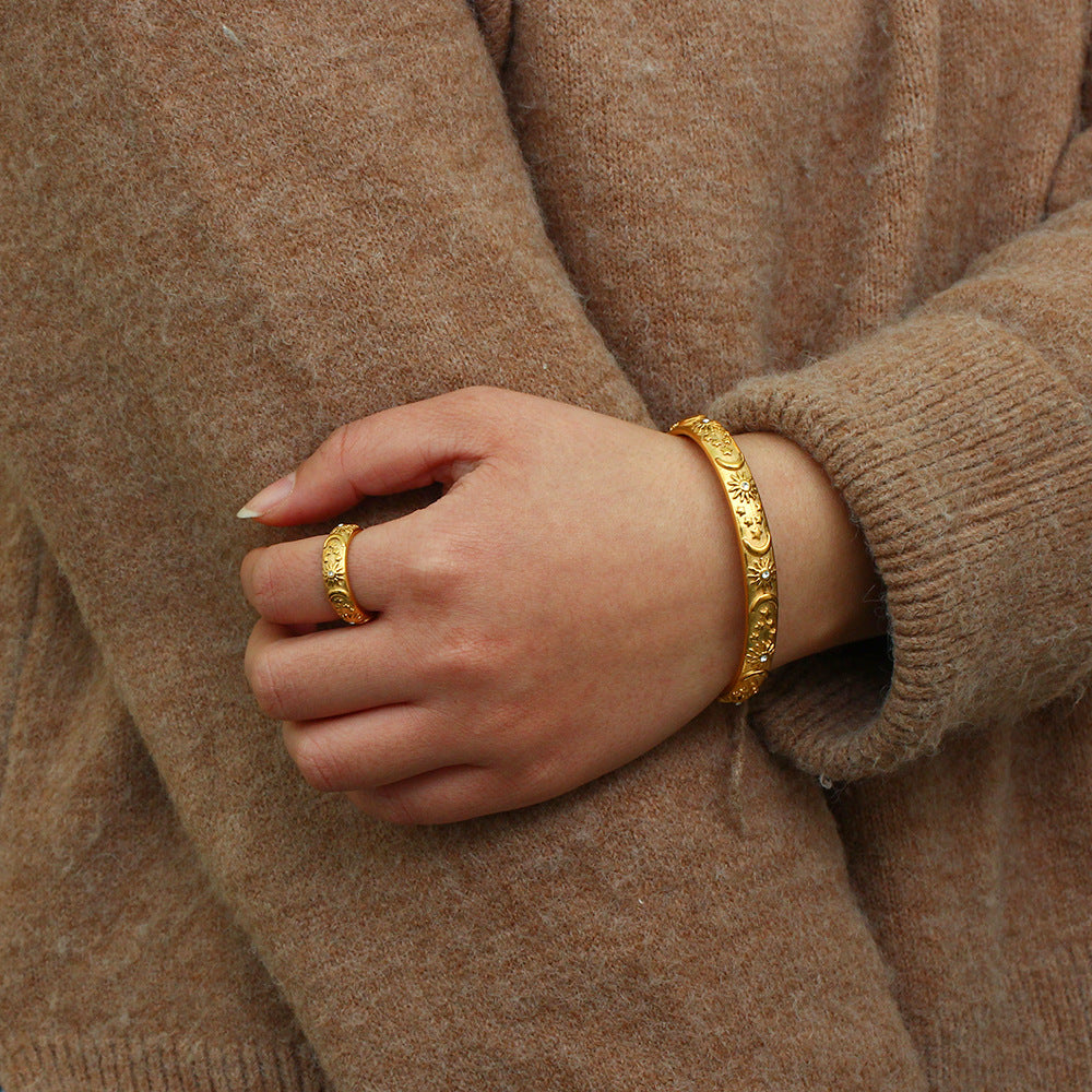 Matching engraved gold ring and bracelet set on model in casual jeans