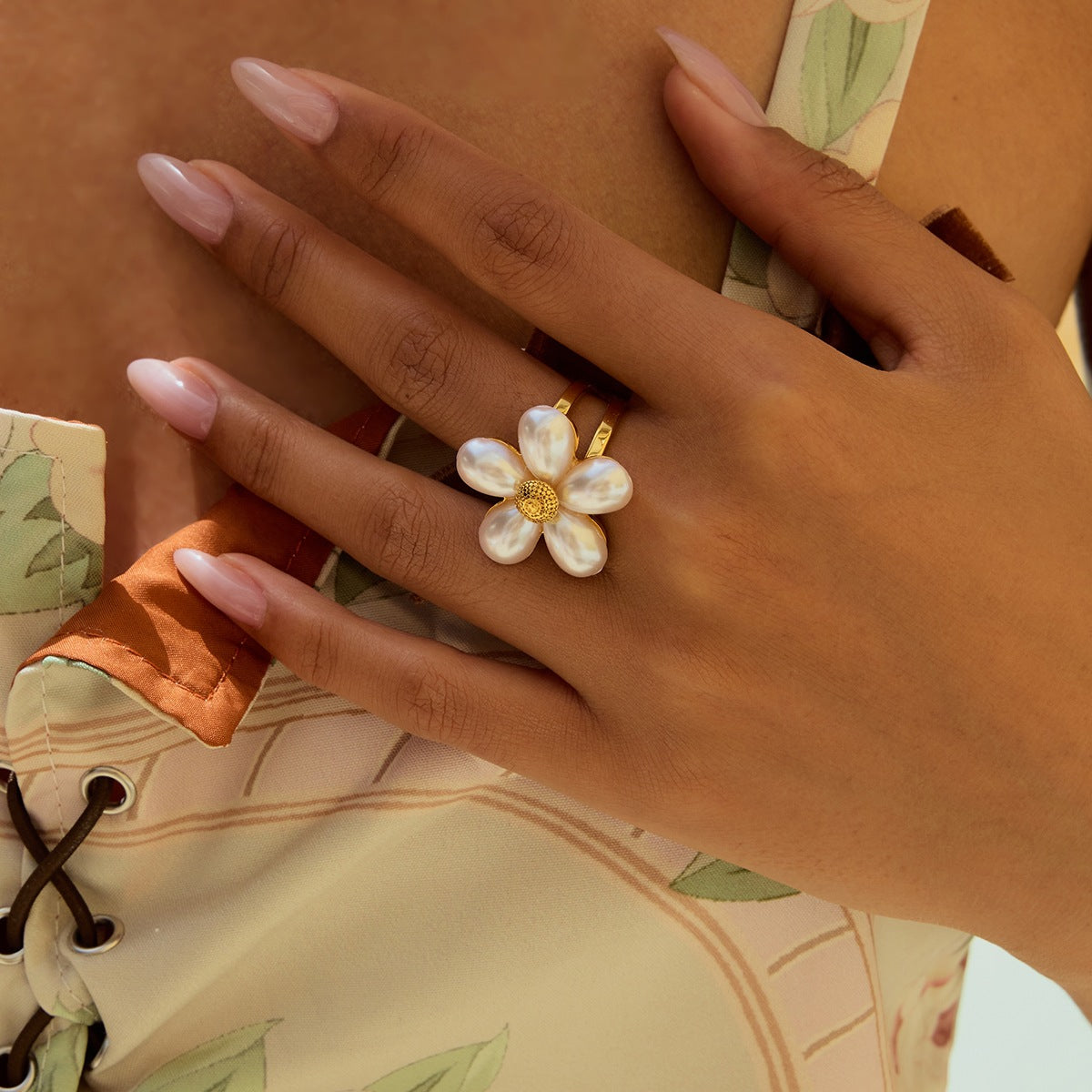 Woman’s hand with floral pearl ring in a summer outfit, feminine nail detail