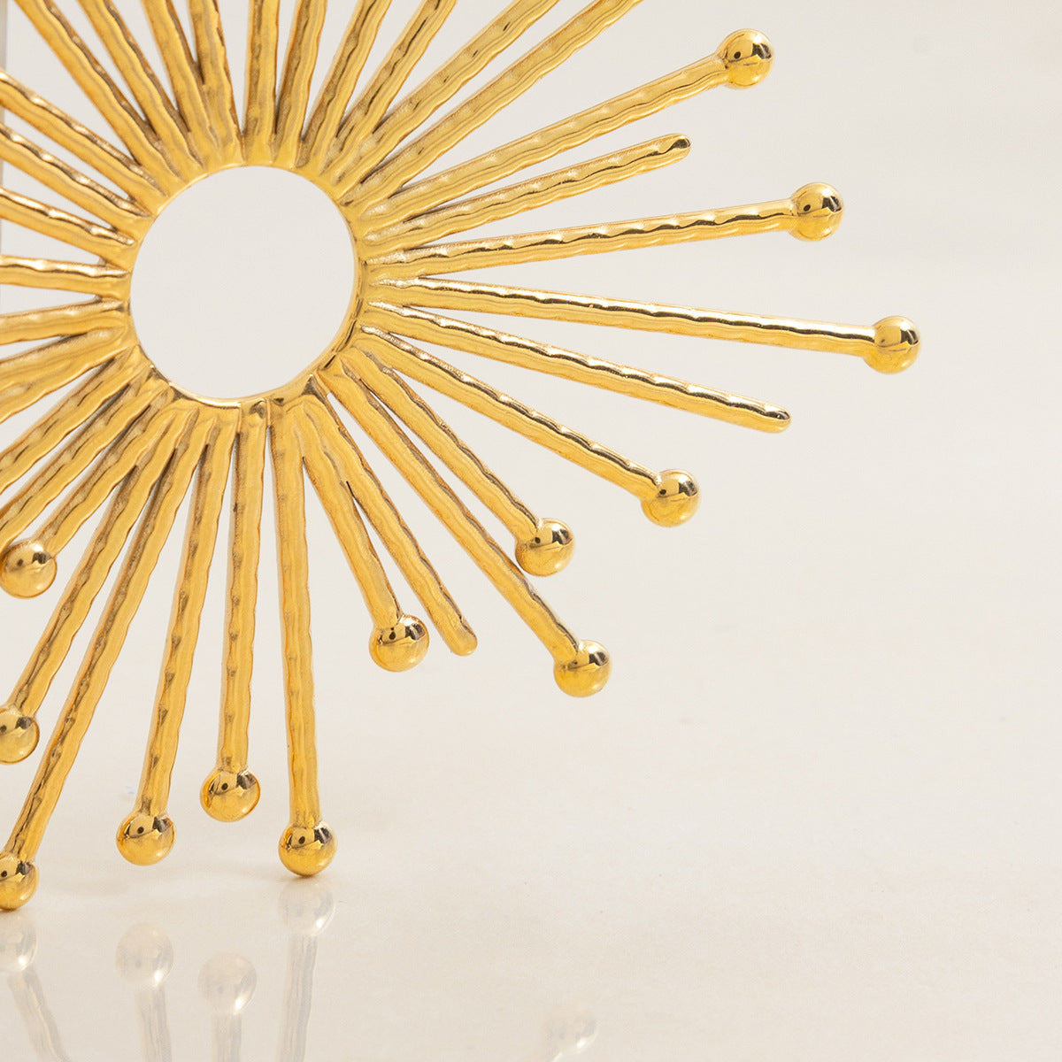 close-up of gold sunburst pendant with hammered texture