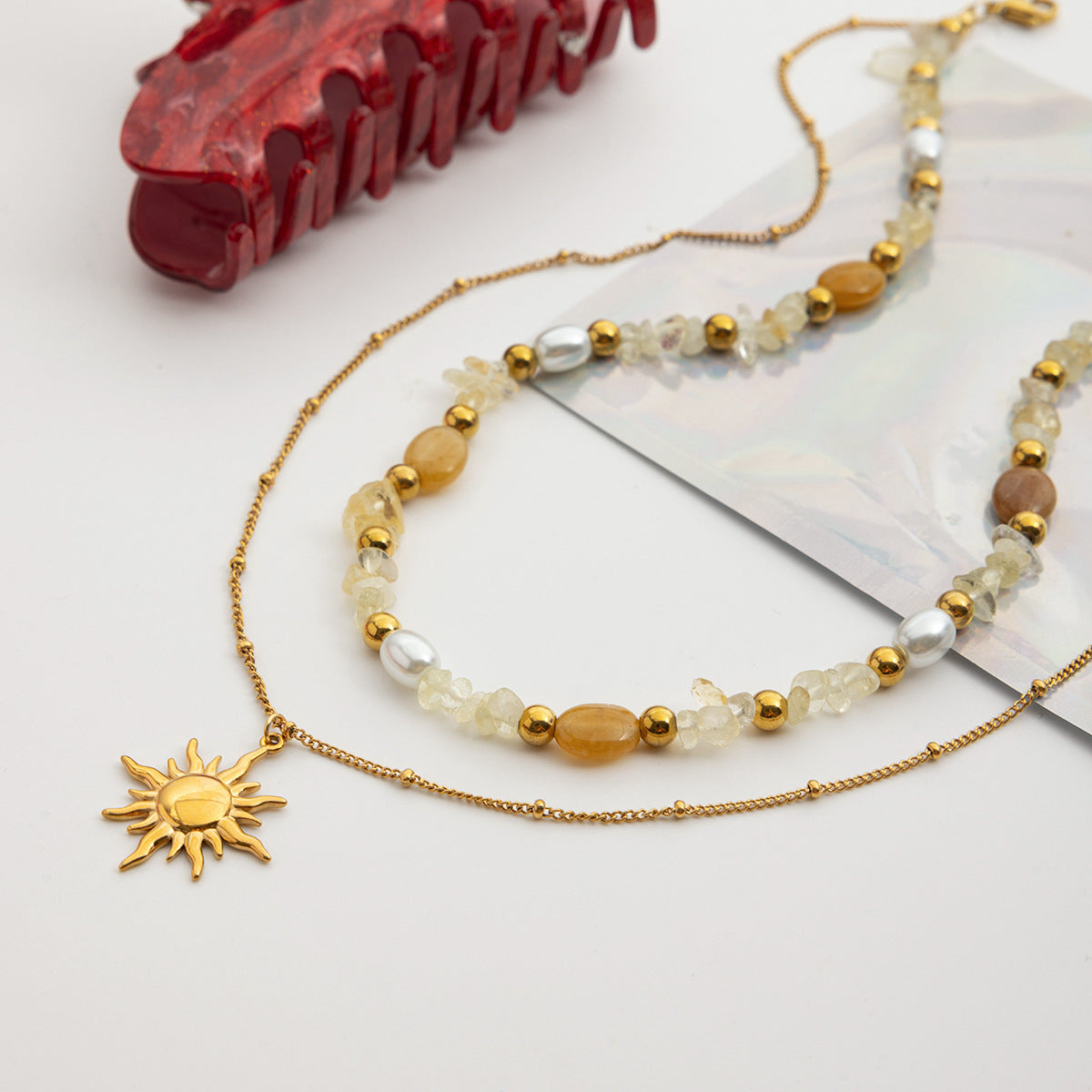 Necklace with sun charm and beaded chain on a white surface