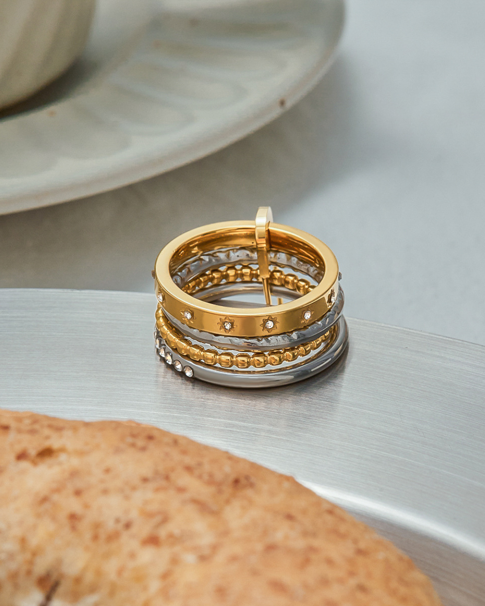 Stack of gold and silver rings on a textured surface with a blurred background
