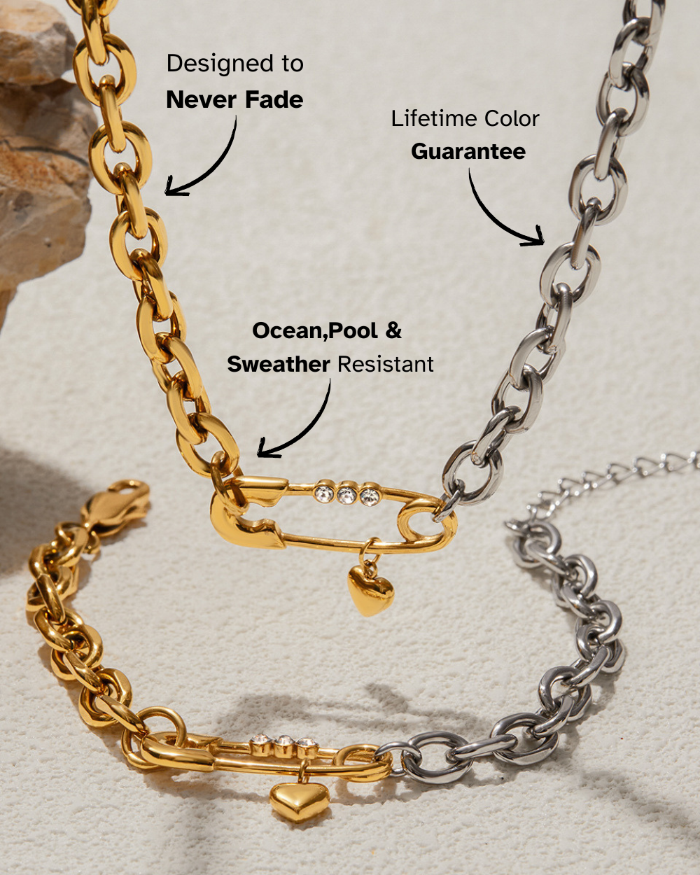 Gold and silver chain bracelets with safety pin and heart charms on a textured surface.
