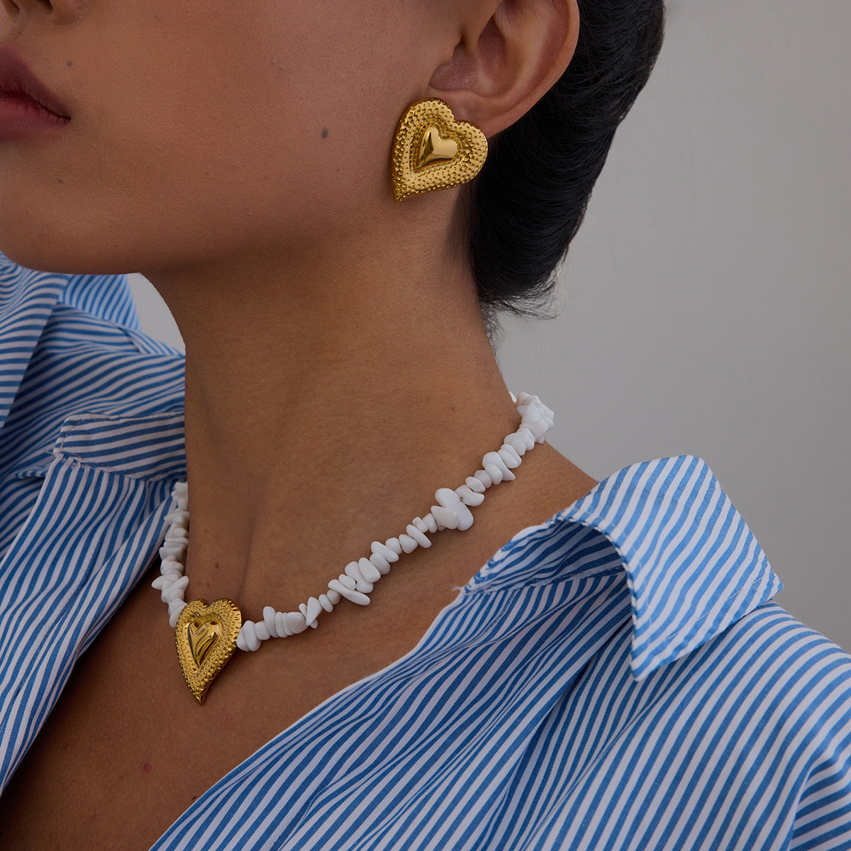 Matching gold heart necklace and earrings styled on model