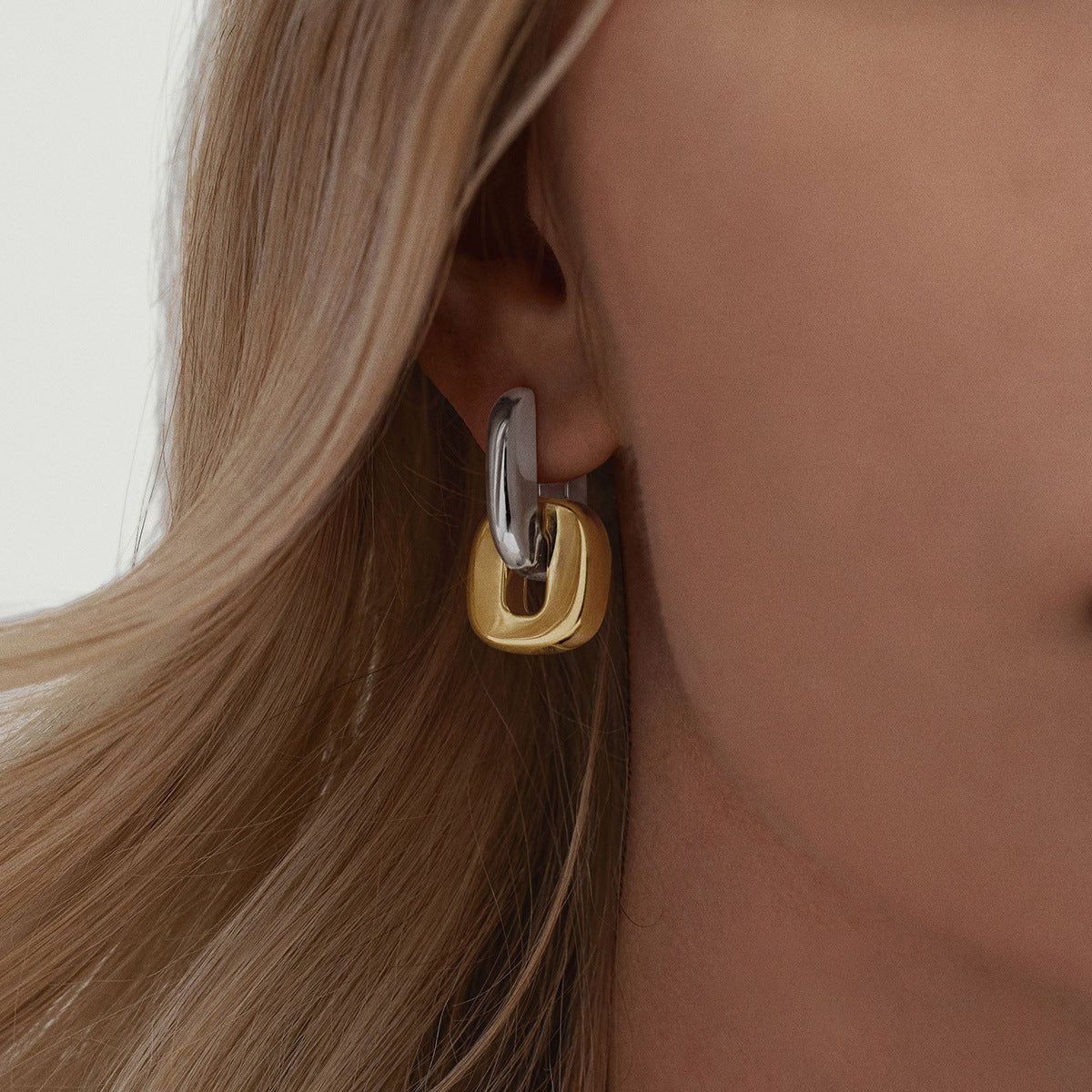 Gold and silver linked drop earrings shown worn by model with blonde hair.