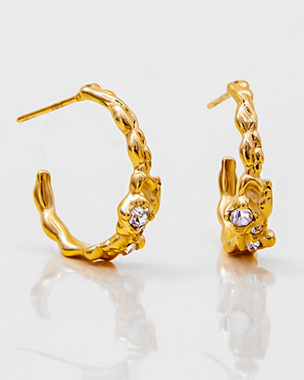 Gold hoop earrings with a textured design on a light gray background