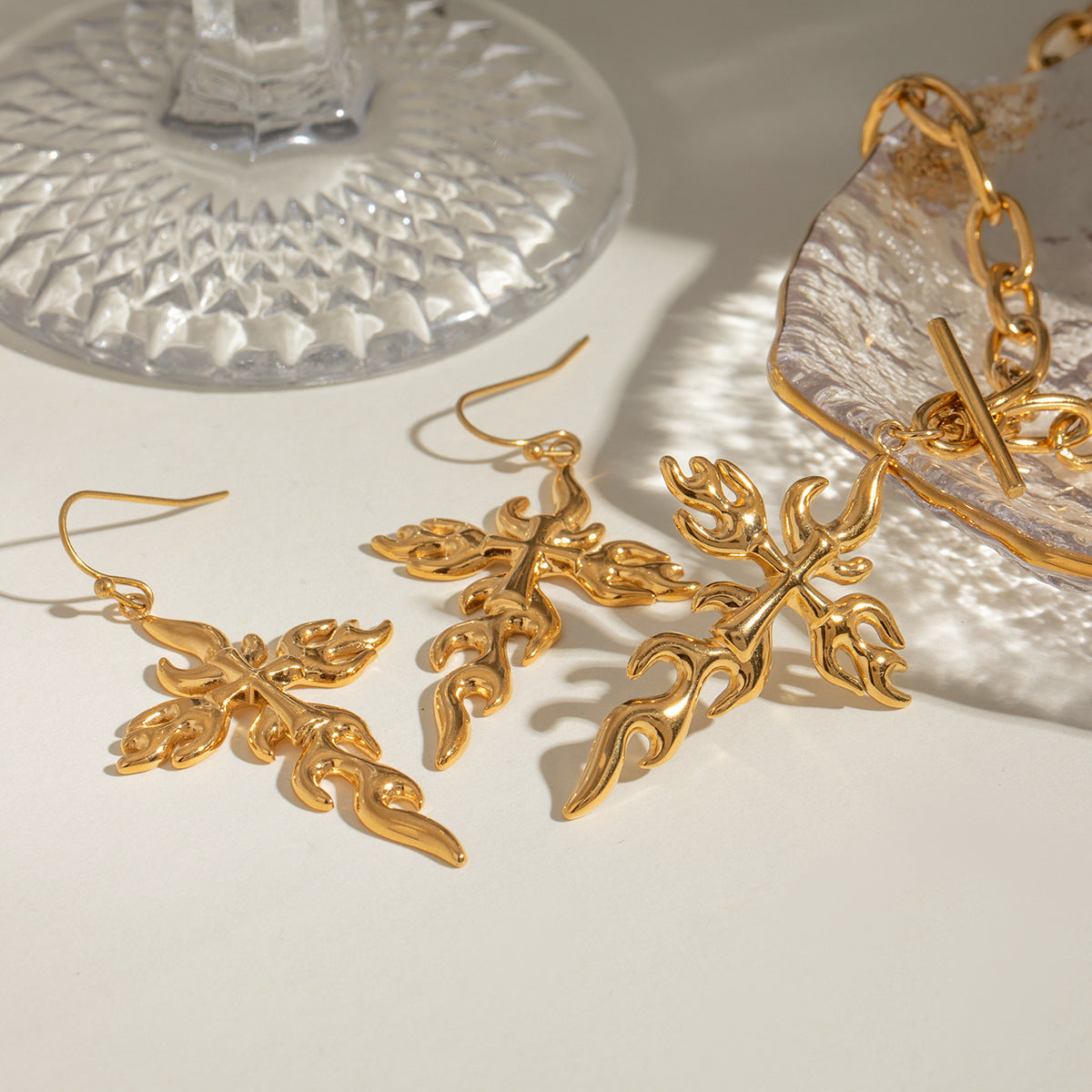 flame pendant necklace flat lay with matching earrings and glass dish