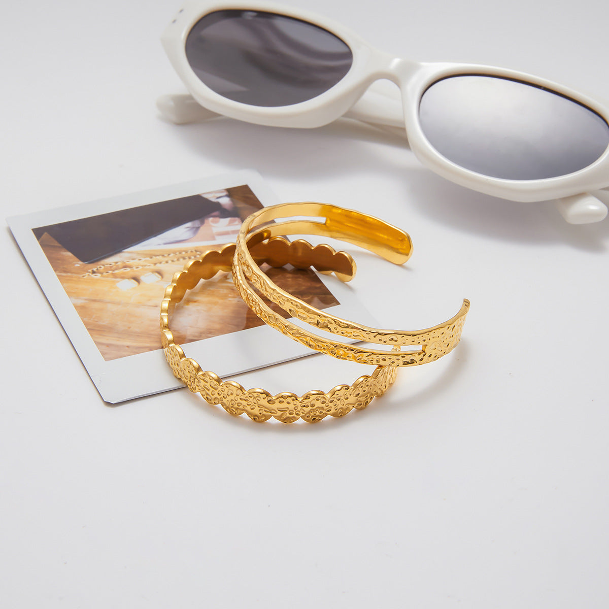 Gold headbands on a white surface with sunglasses and a photo in the background