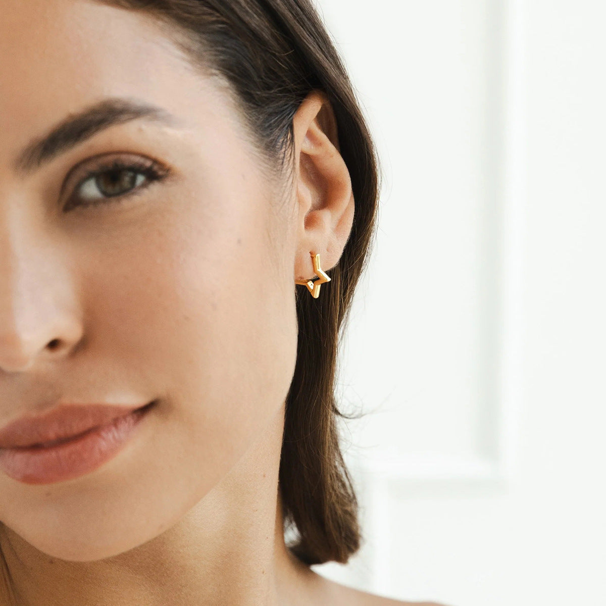 Model wearing small star hoop earrings with sleek hairstyle