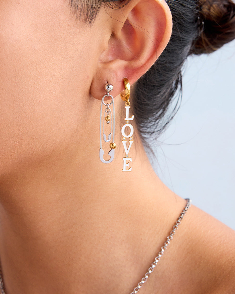 Trendy mismatched earrings styled for a bold fashion look with mixed metal details.