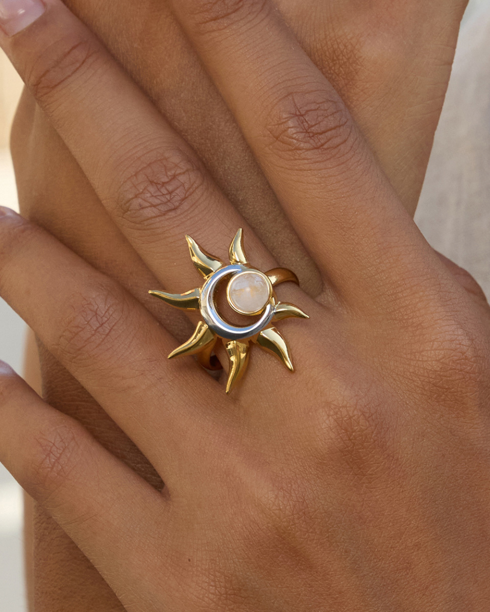 Gold ring with sun and moon design on a person's finger