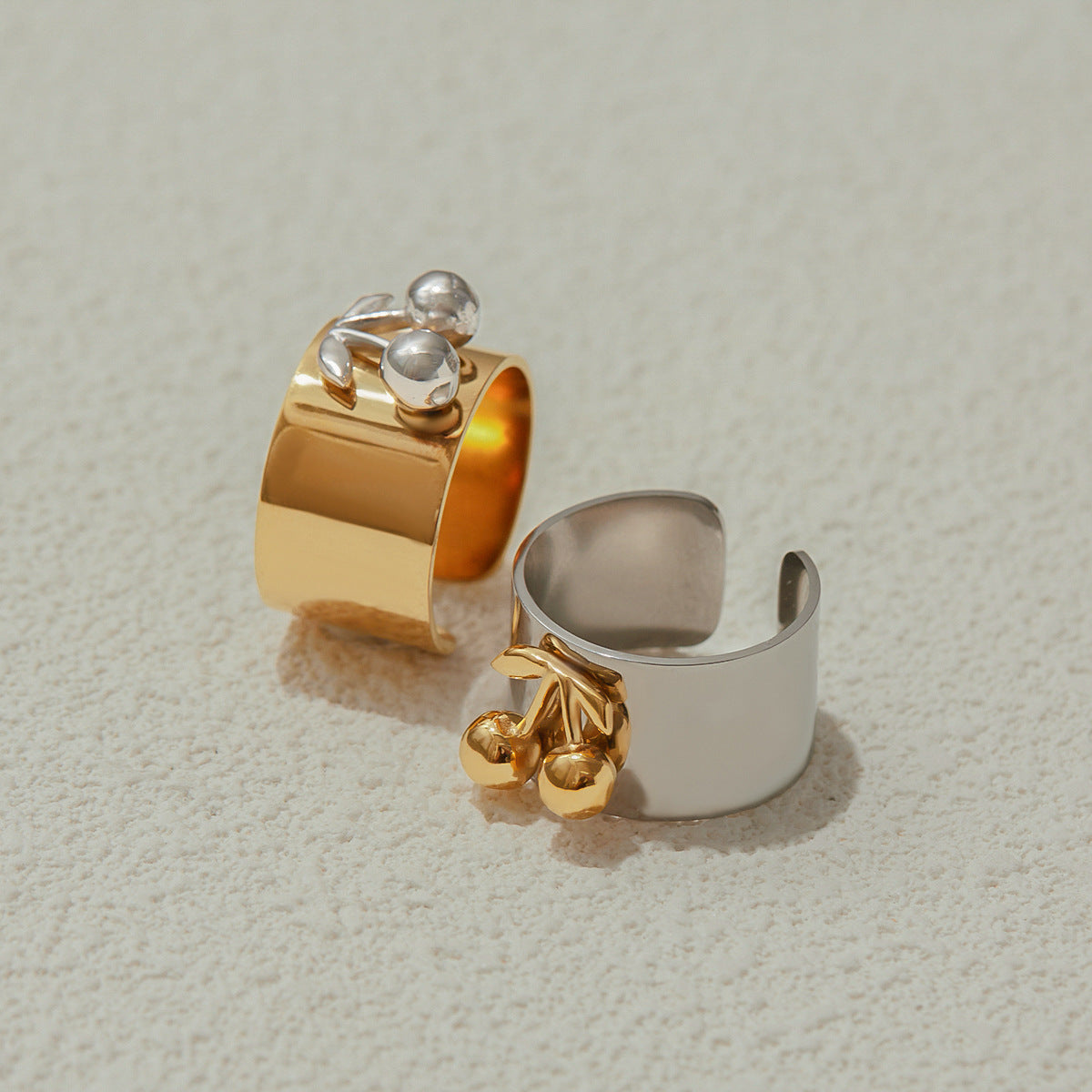 Hand wearing chunky cherry ring with gold fruit detail, styled by the pool