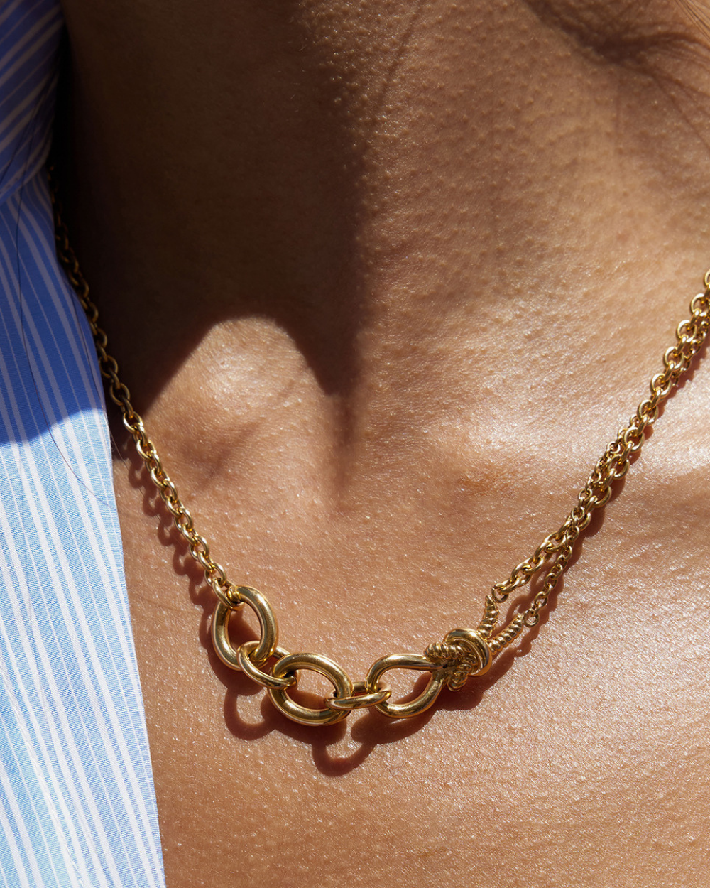 Gold chain necklace on a person's neck with a blurred background