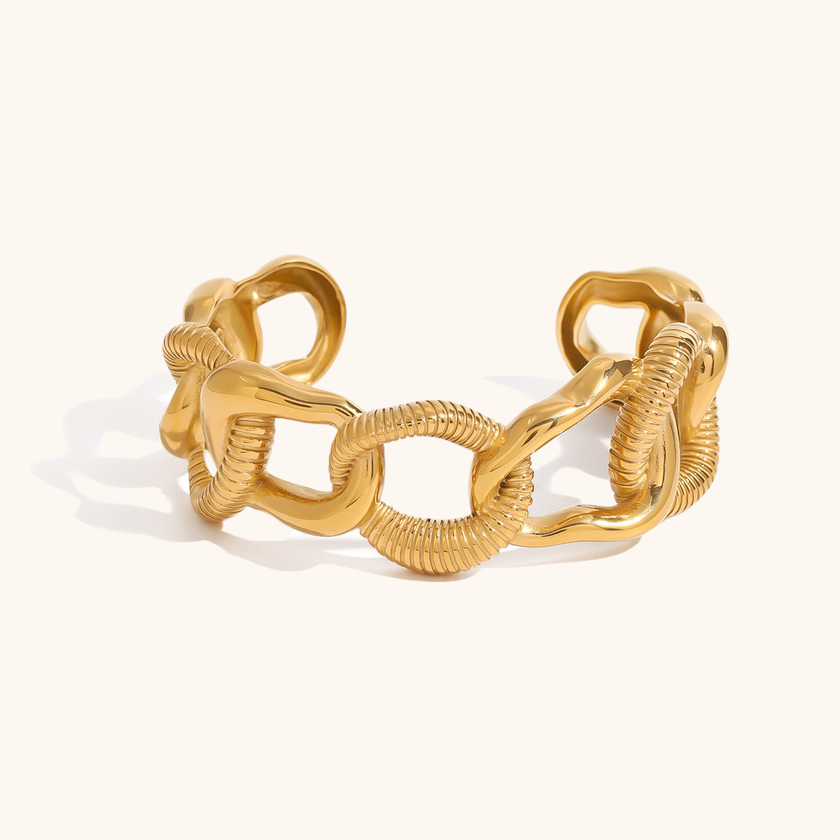 Close-up of sculpted open cuff bracelet in gold with irregular chain design