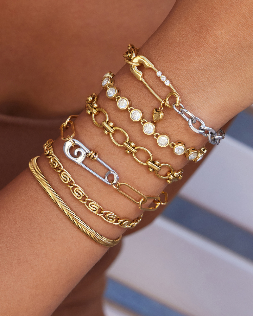 Multiple gold and silver bracelets on a wrist with a blurred background