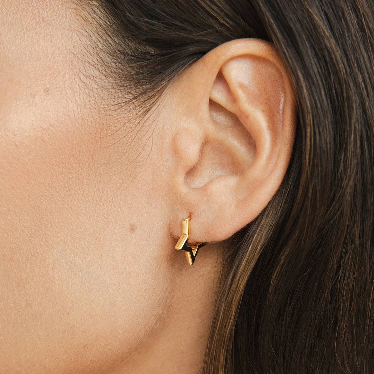Close-up of star earrings on ear in natural light