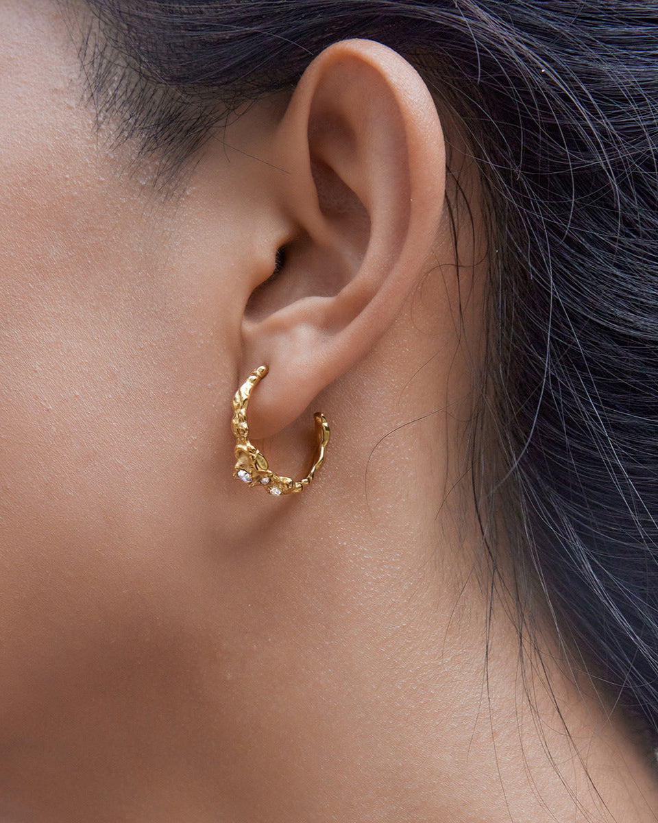 Gold hoop earring worn by a person with dark hair.