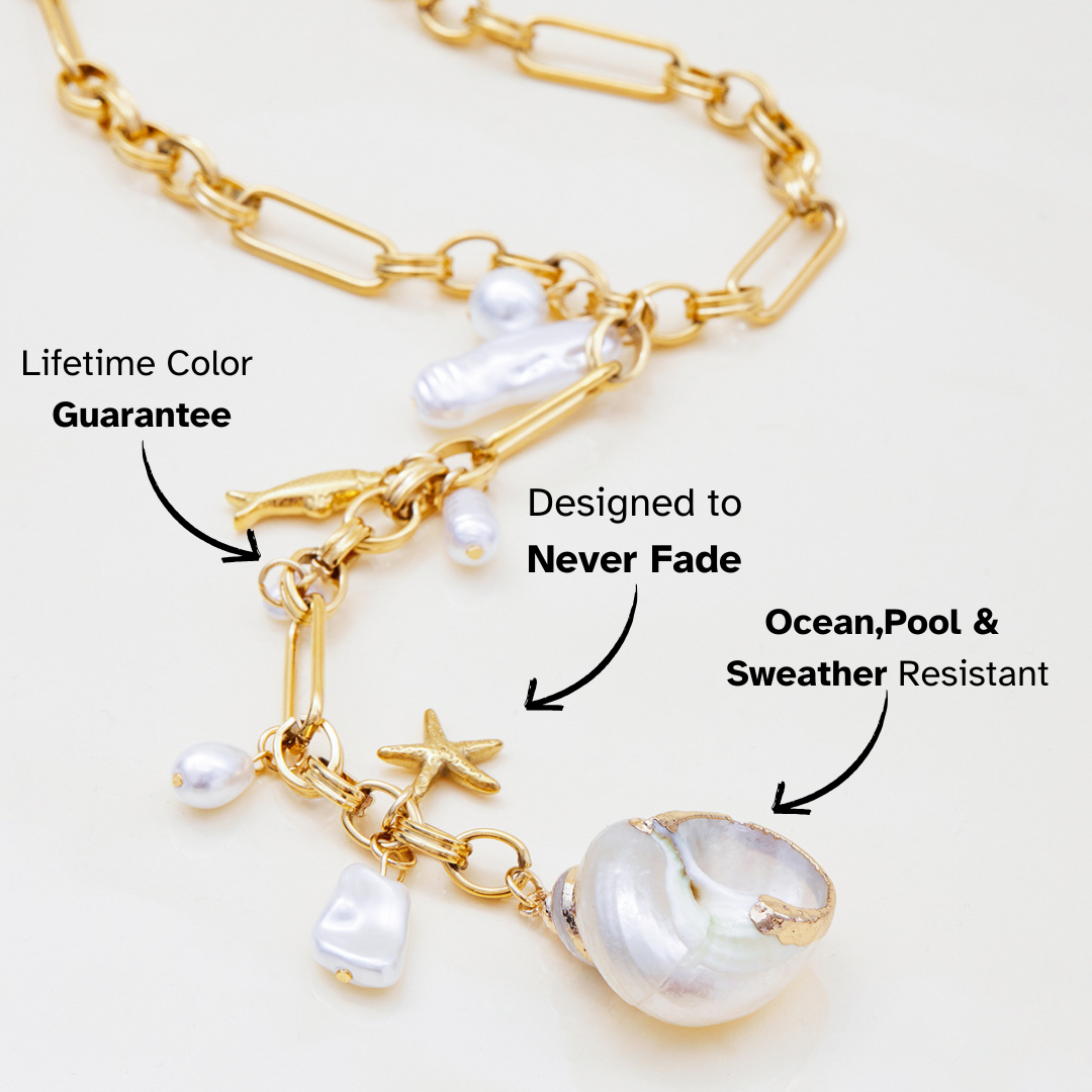 Gold chain necklace with pearls and charms on a white background