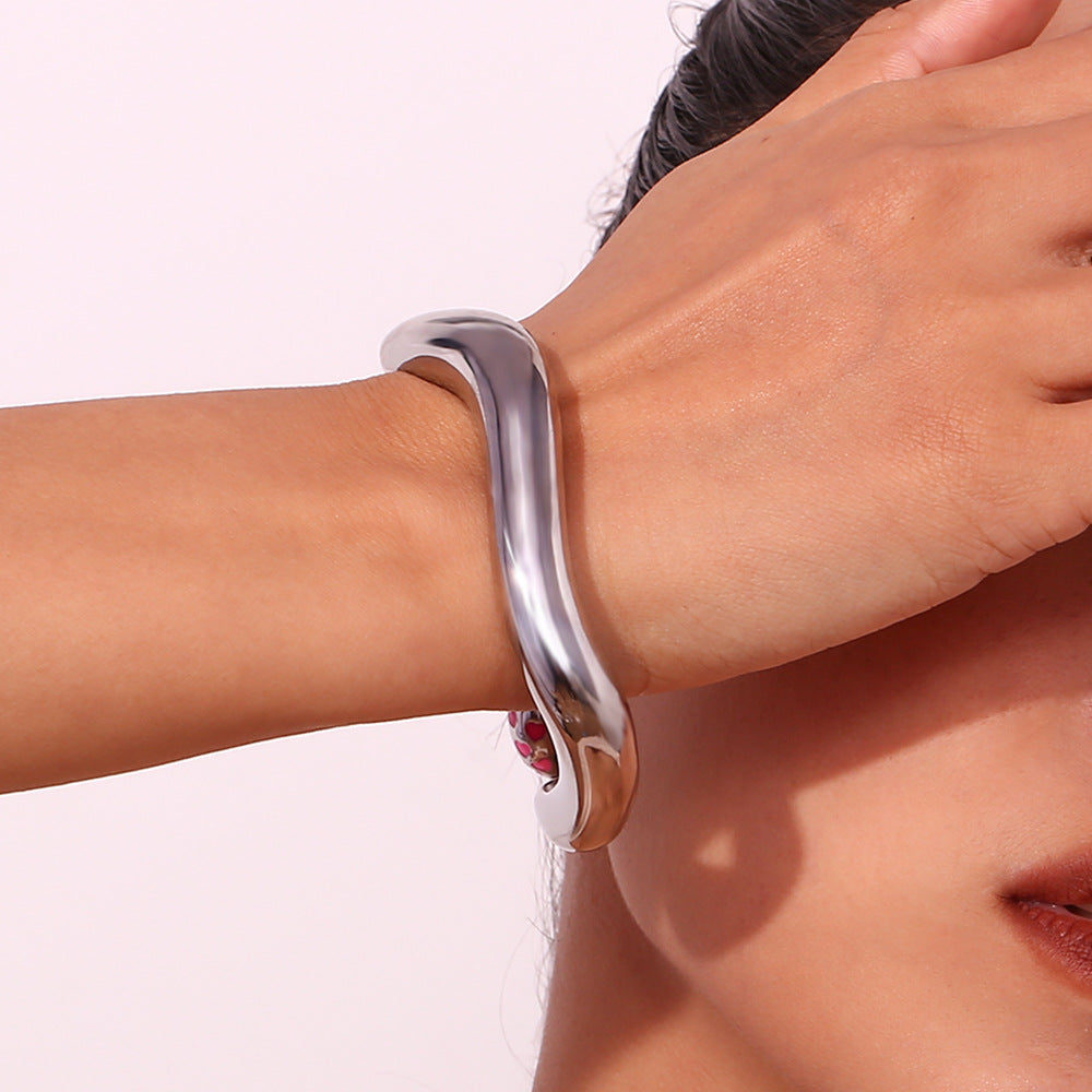 Sculptural wave cuff on model’s wrist paired with dainty rings