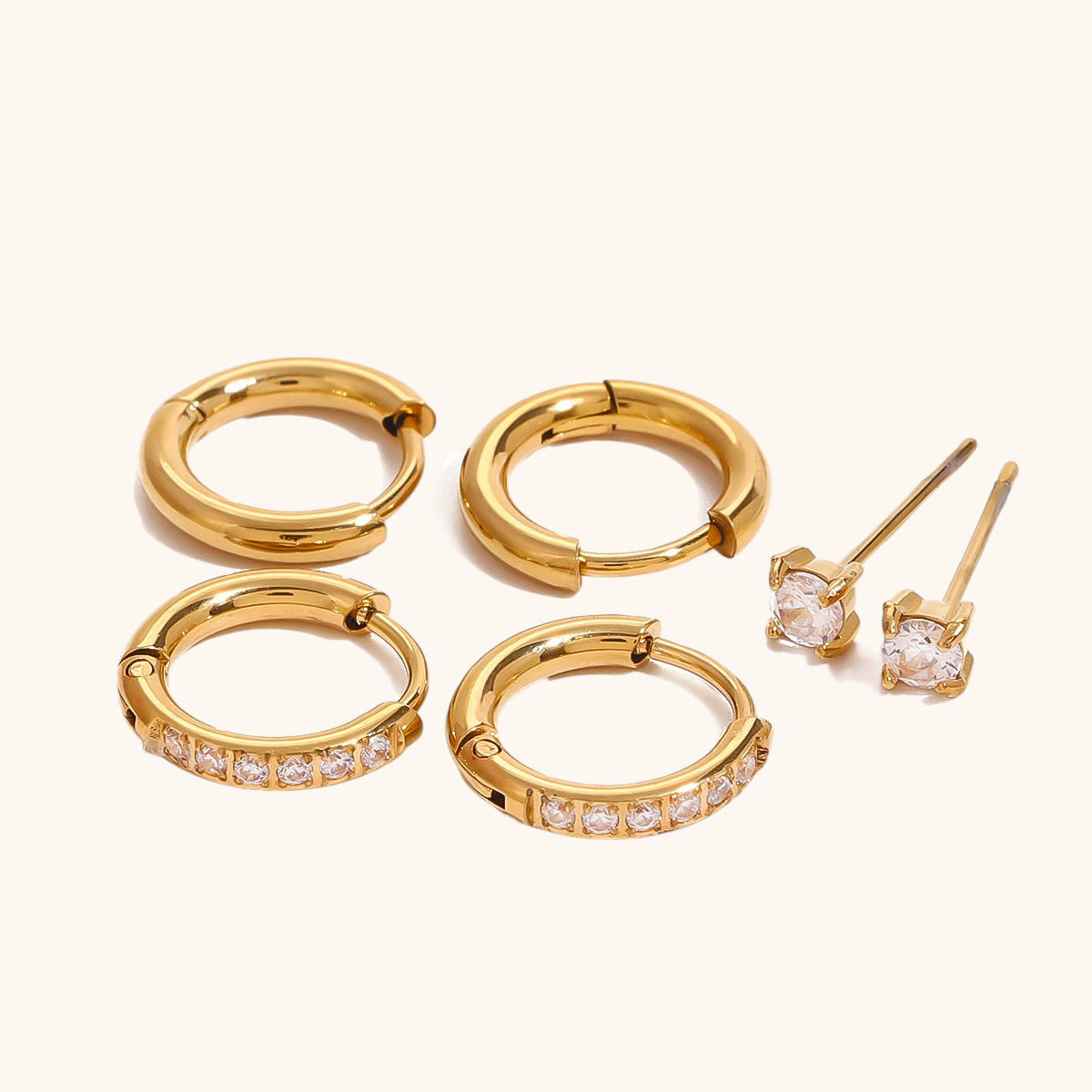 Minimalist gold hoop earrings with a polished, smooth finish, displayed on beige background.