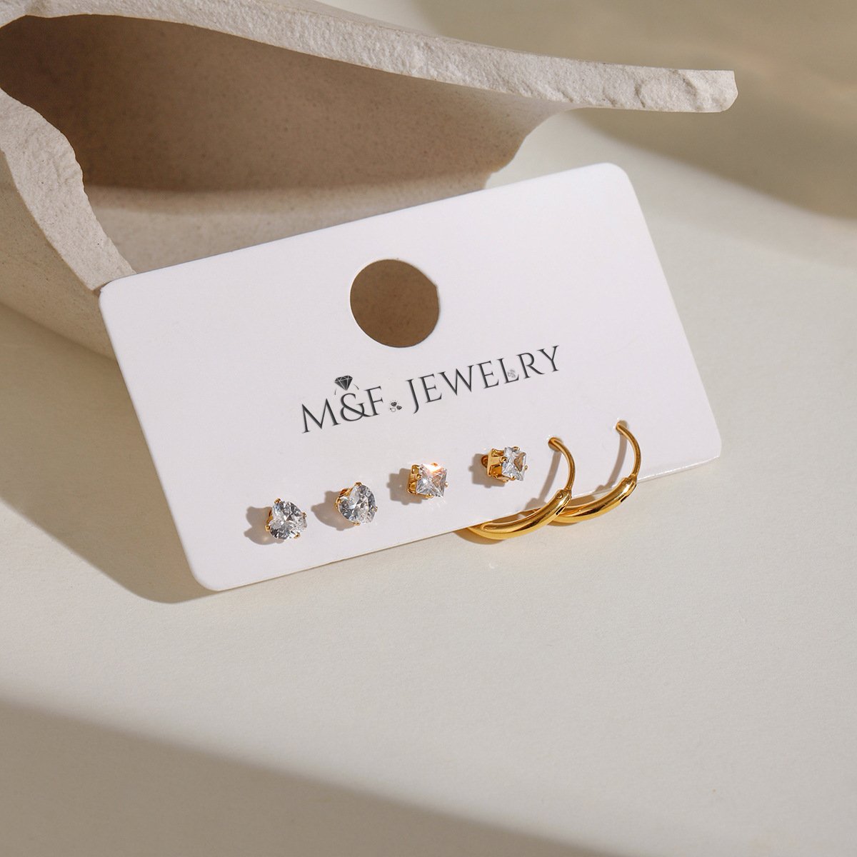 Gold hoop earrings and mixed crystal studs displayed on M&F Jewelry card