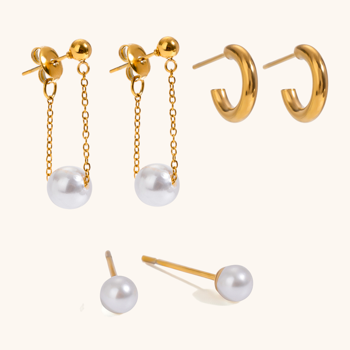 Studio close-up of gold hoop earrings, small pearl studs, and long chain pearl drop earrings
