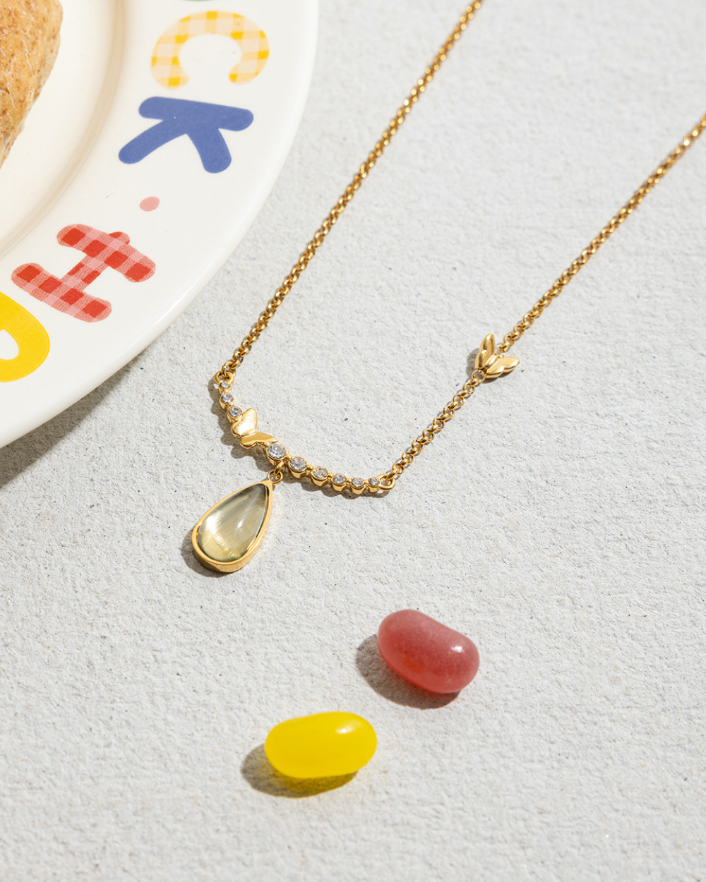 Gold necklace with colorful pendant on a light gray background