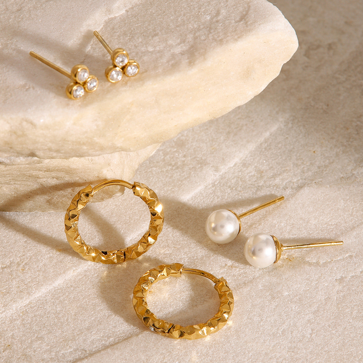 Minimalist white pearl stud earrings with gold post, styled on neutral marble surface
