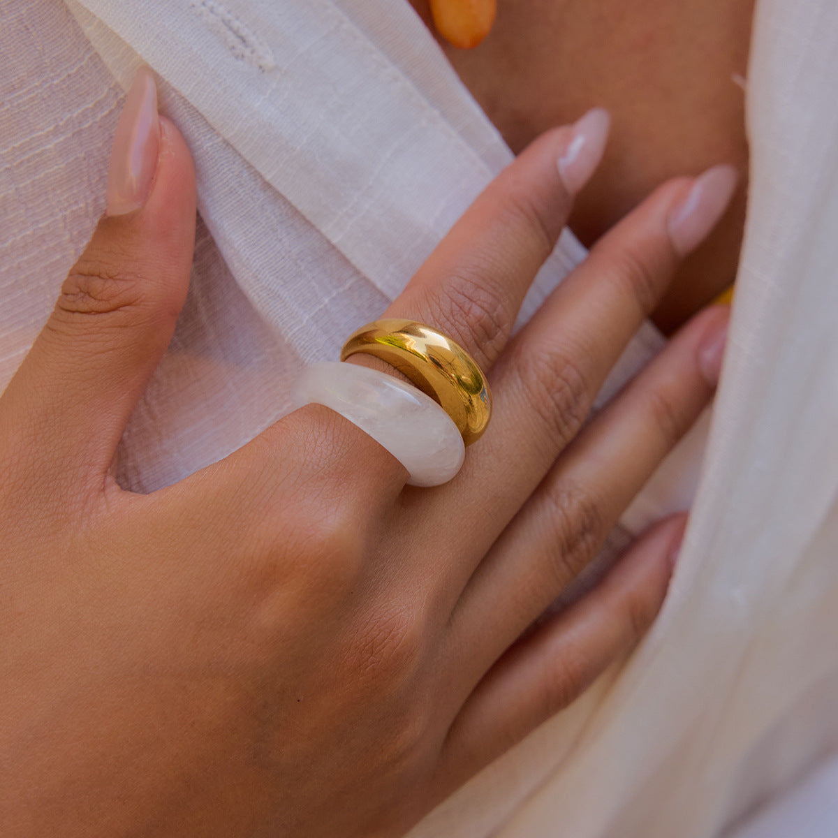Transparent dome-shaped ring styled on model's hand with layered gold ring.