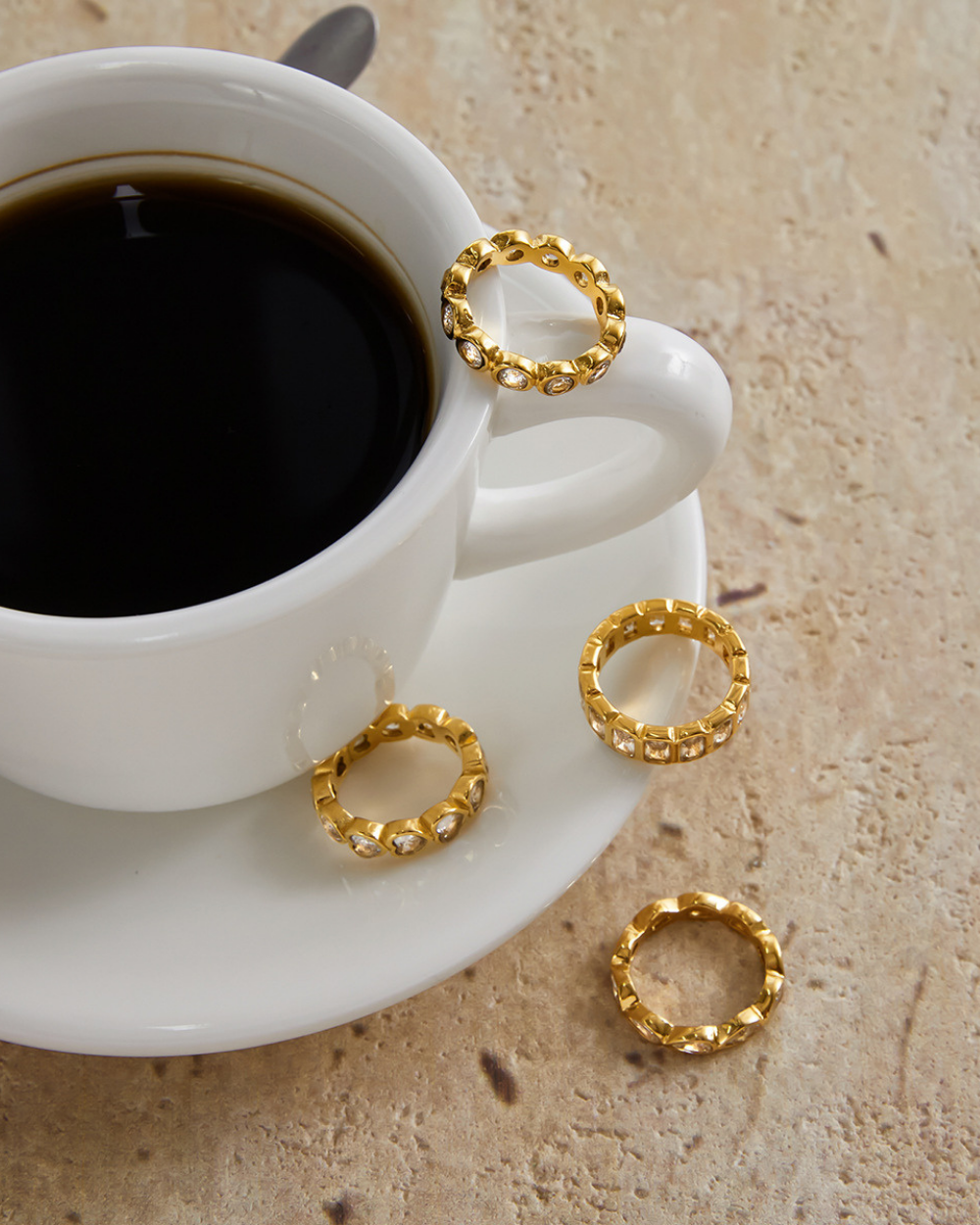 White cup of coffee with gold rings on a beige surface