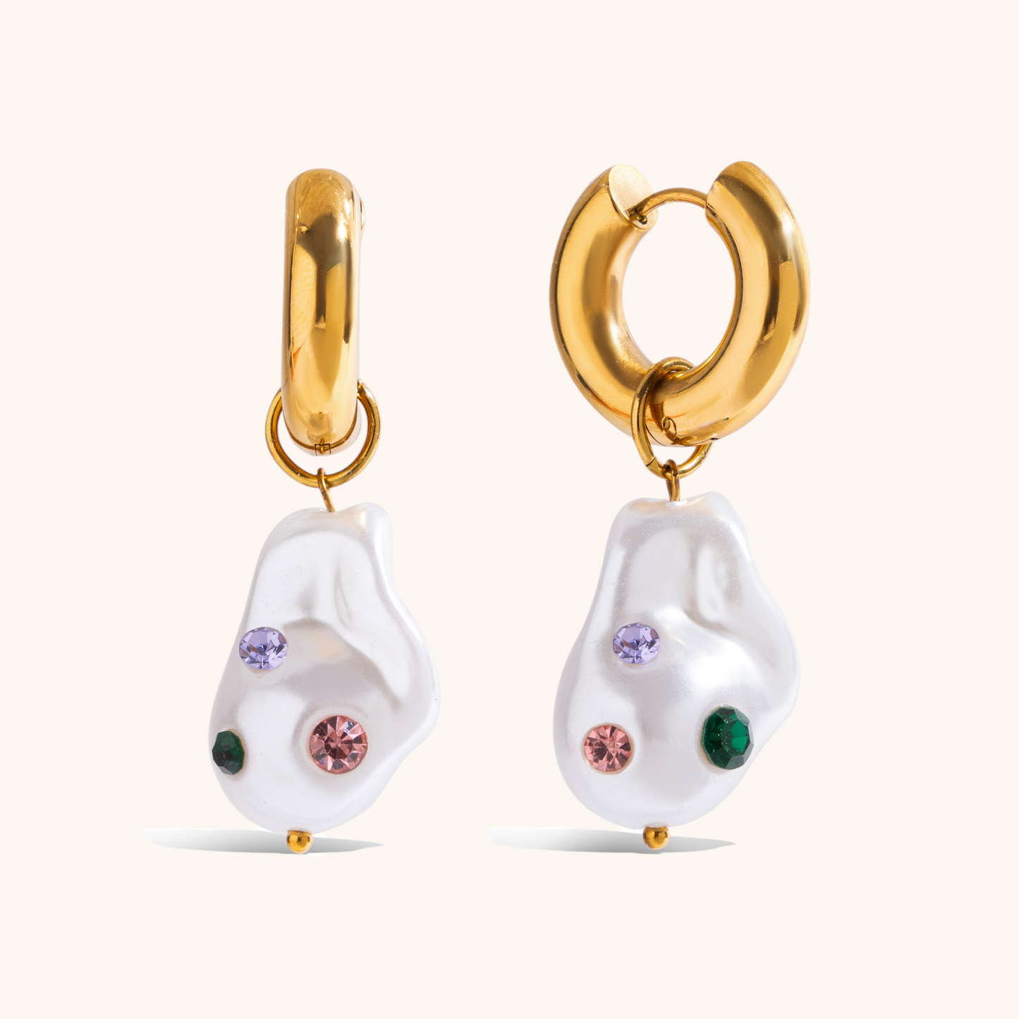 Irregular pearl earrings with colorful gemstones on a plate