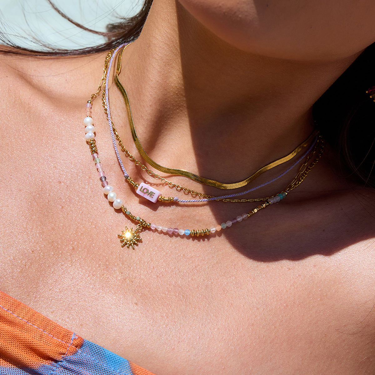 Close-up of waterproof pearl and sun charm necklace on skin