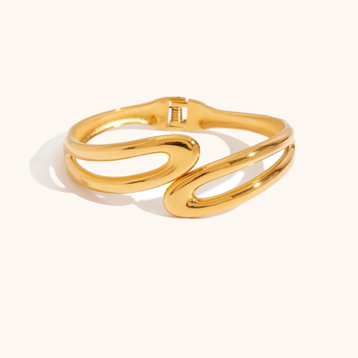 High-shine gold open-loop bracelet photographed with soft shadows
