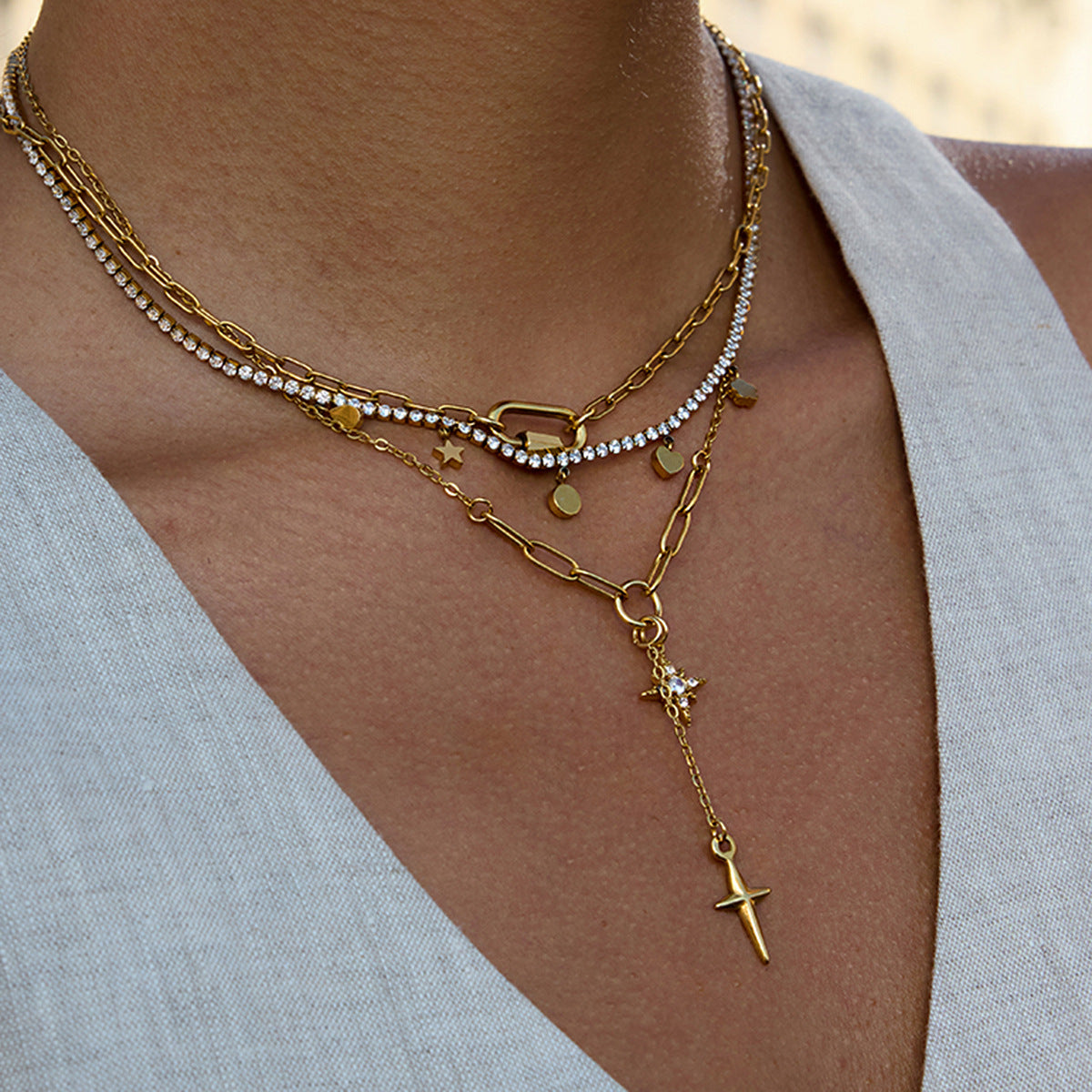 Layered gold and pearl necklaces on a person wearing a light gray top.