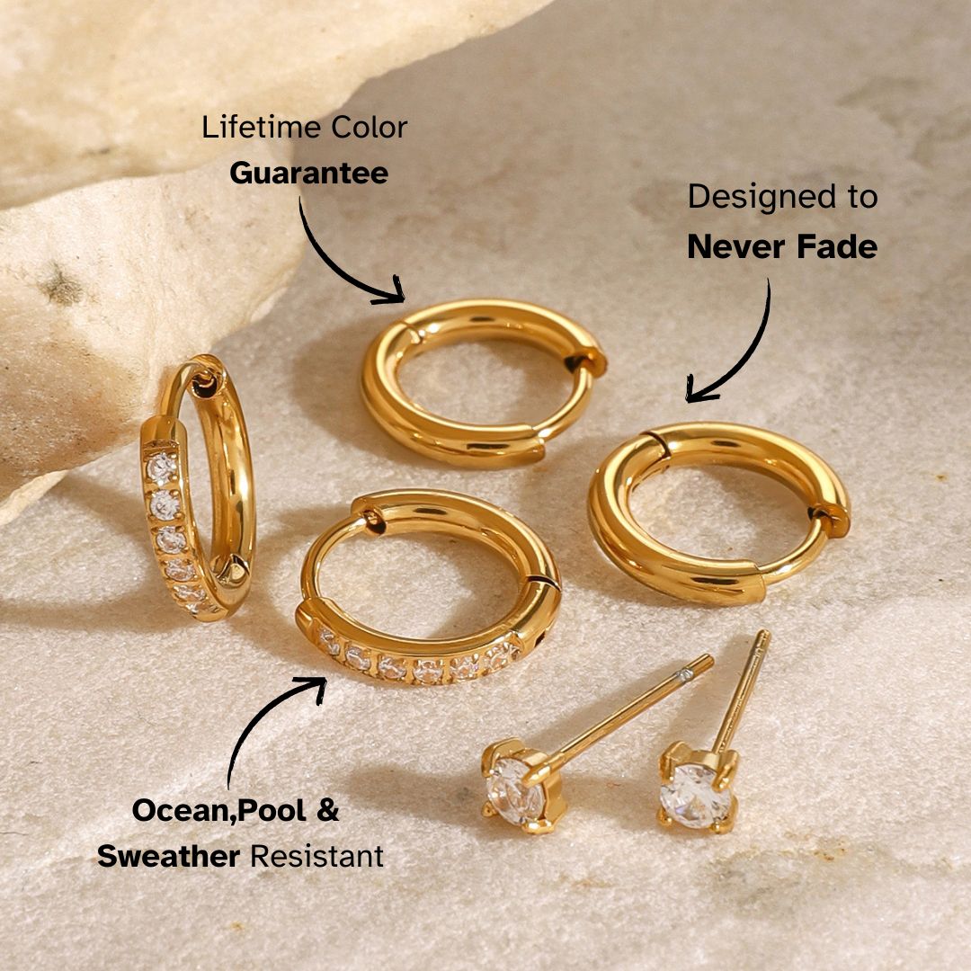 Gold huggie hoop earrings adorned with clear cubic zirconia stones, placed near stone decor.