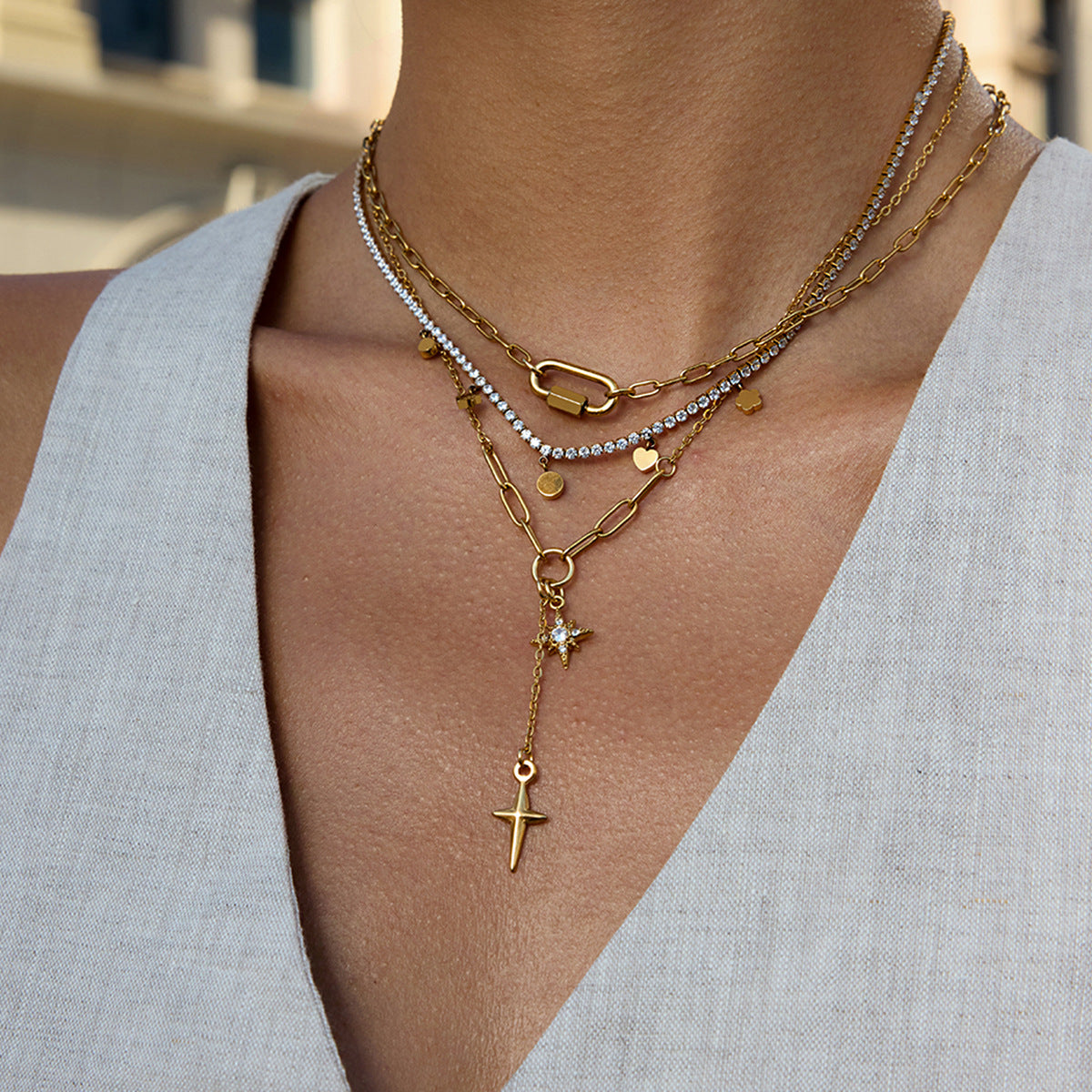 Close-up of a person wearing multiple gold necklaces with various pendants.